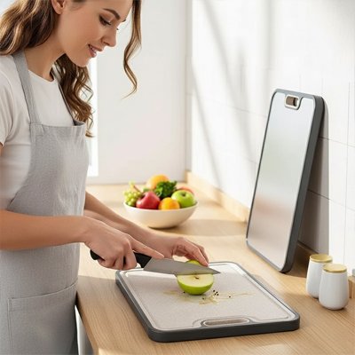 Une femme coupe une pomme verte en deux sur sa nouvelle planche à decouper en titane.